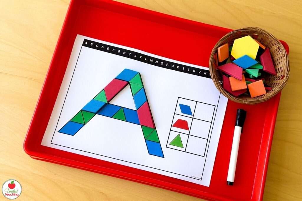 Colorful pattern blocks forming the uppercase letter A on an alphabet pattern block mat displayed on a red activity tray, with a recording table for counting each shape used