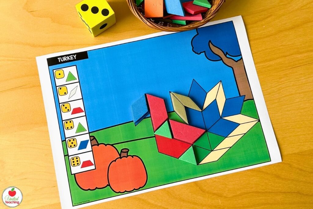 Roll and build Thanksgiving turkey pattern block mat with pumpkins and an autumn tree scene, where students roll a die and place the matching shape to build the turkey