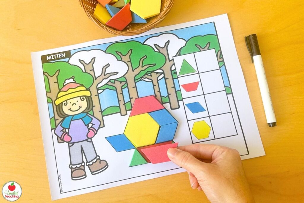Hand placing a red pattern block on a winter mitten mat with a snowy forest scene, where students build the mitten shape and count each shape used in the recording table