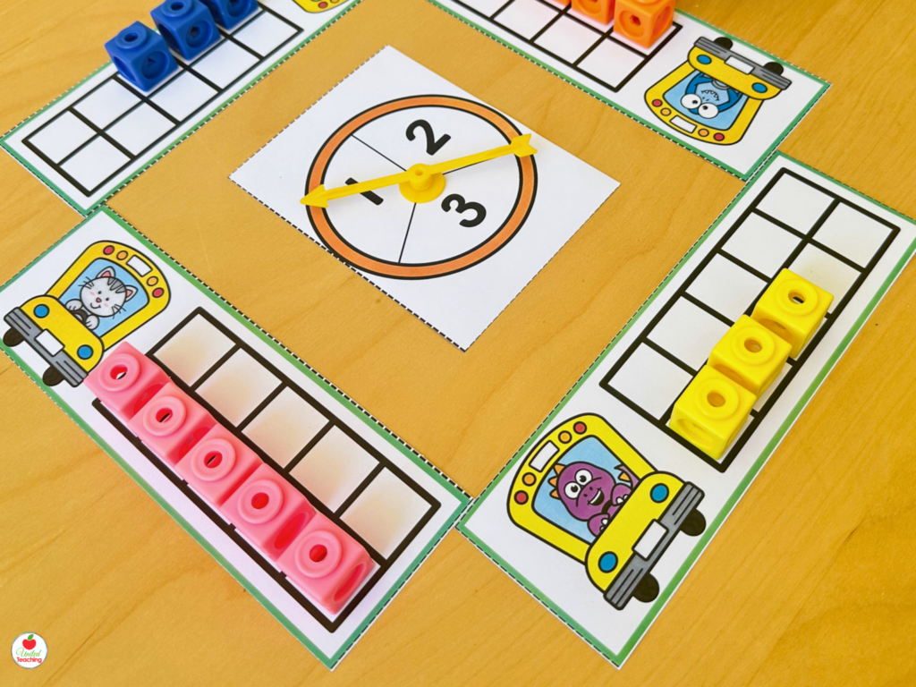 Race to 10 ten frame game showing four bus-themed player mats with a spinner in the center and math cubes on the frames
