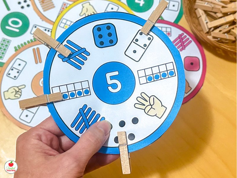 Subitizing clip card for number 5 with multiple clothespins attached to matching number representations for self-checking kindergarten math practice