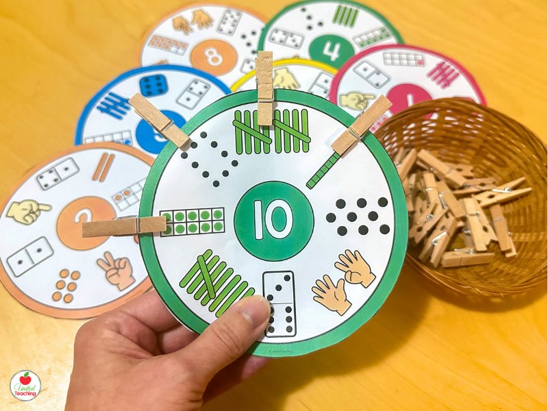 Set of subitizing clip cards spread on a table showing numbers 5 and 10 with a basket of clothespins for kindergarten math centers