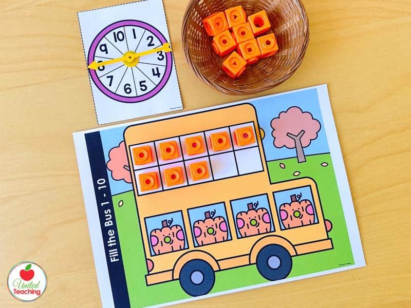 Pumpkin Fill the Bus ten frame mat for numbers 1 to 10 with orange math cubes and a 1 to 10 spinner