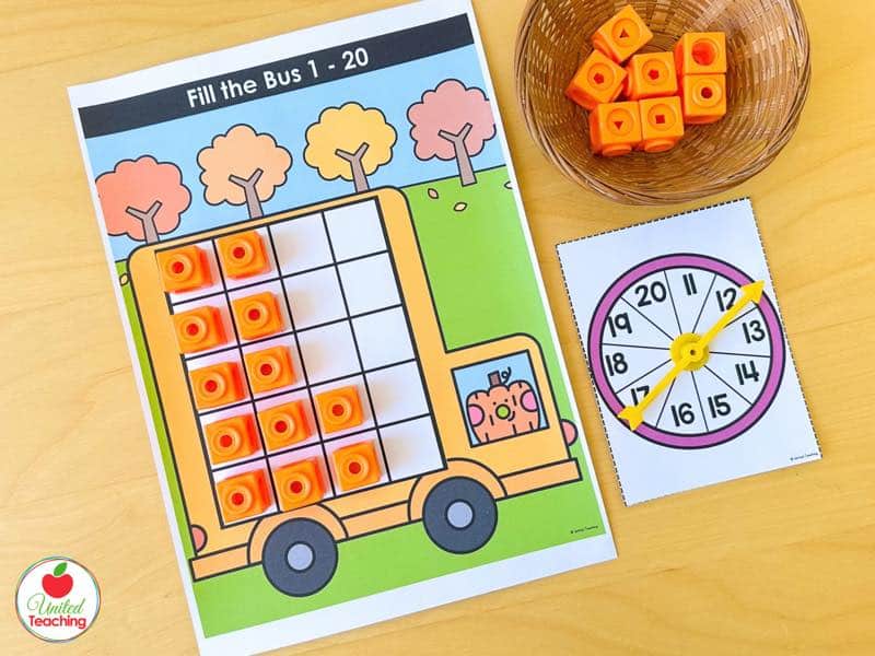 Pumpkin Fill the Bus ten frame mat for numbers 1 to 20 with orange math cubes and an 11 to 20 spinner